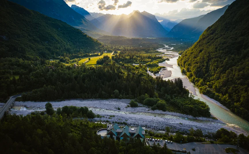 Raggi di sole su una valle fluviale e montagne al tramonto