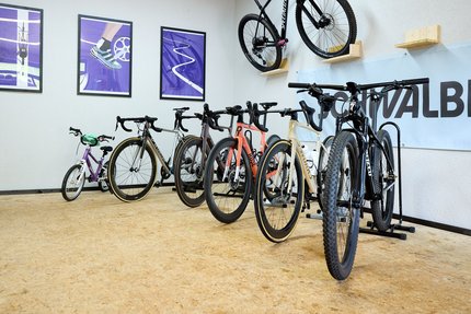 Verschillende fietsen staan en hangen aan de muur in een kamer met houten vloer