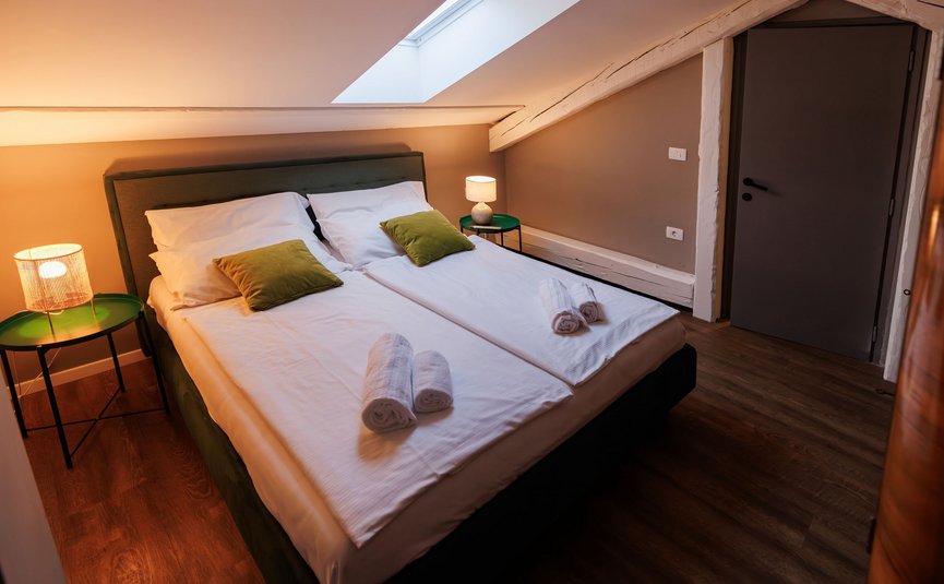 Cozy bedroom with double bed, green pillows, and soft lighting