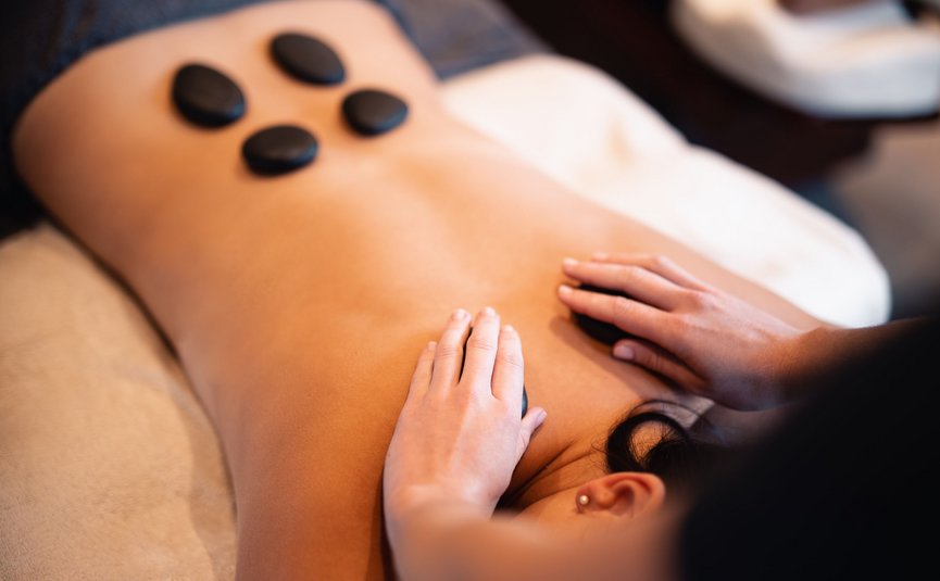 Person receiving a hot stone massage with black stones on their back