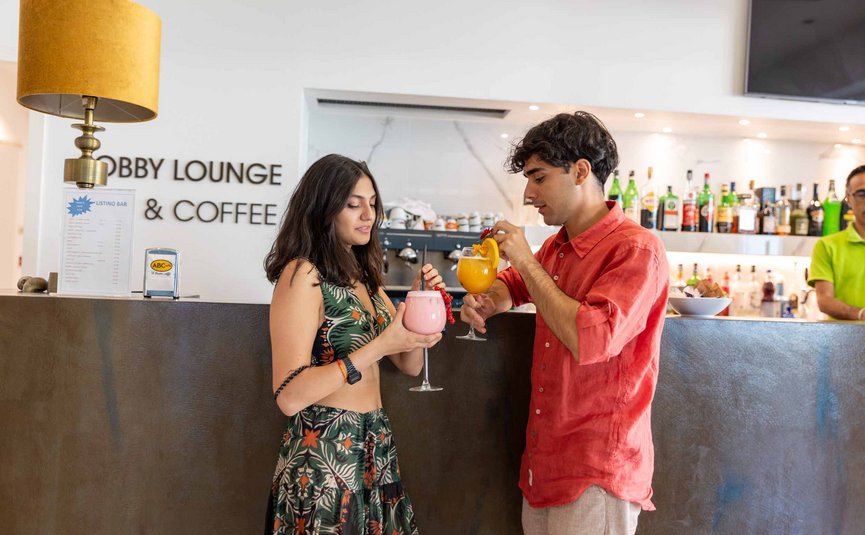 Giovani che assaggiano cocktail in un bar con scaffale di liquori sullo sfondo