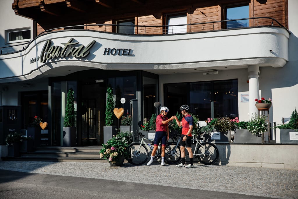 7-days Roadbike Package Two cyclists fist bump in front of Central Hotel with their bikes