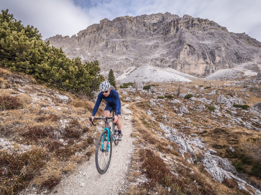 Cyclist riding on mountain trail with rocky peak behind