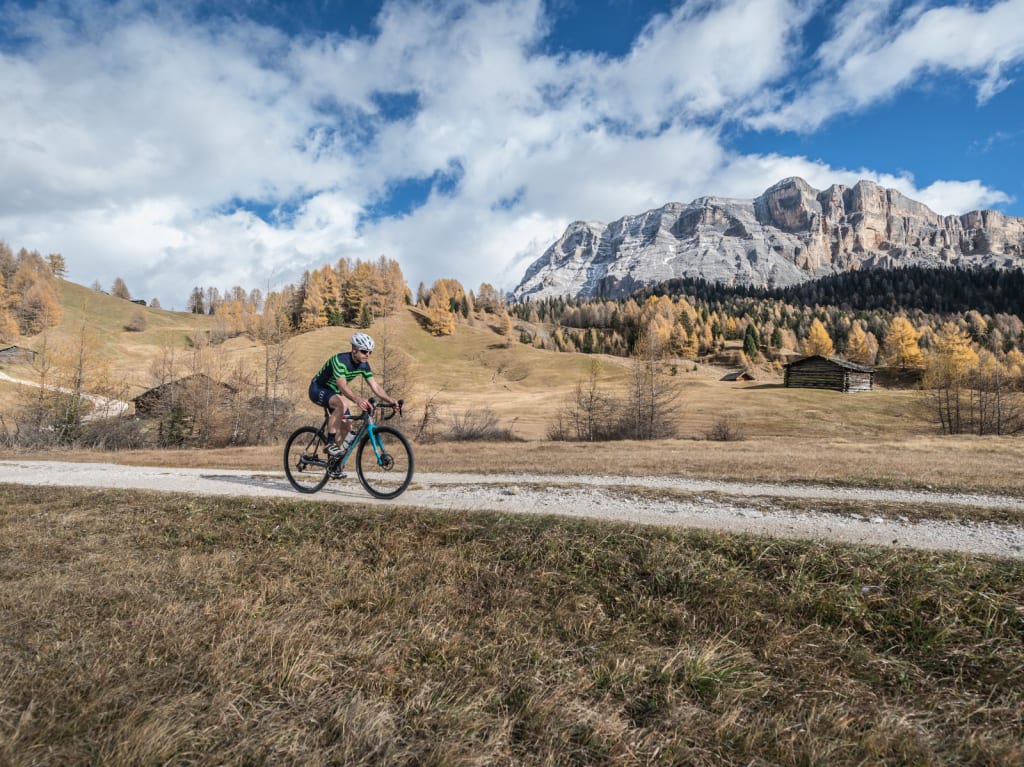 Radfahrer auf gravel bike auf einem Weg in herbstlicher Berglandschaft