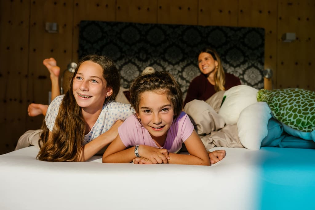 KIDS FREE Twee meisjes en een vrouw ontspannen op een bed