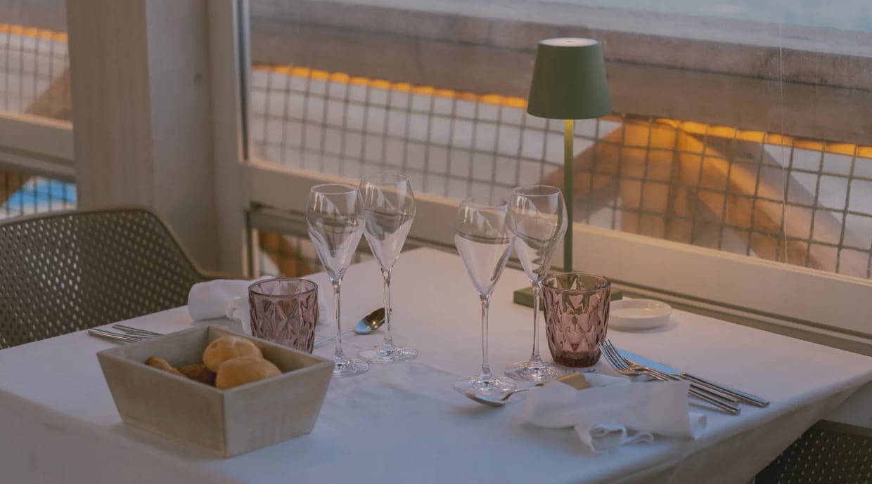 Gedeckter Tisch im Restaurant mit Brotkorb und Gläsern bei Fenster