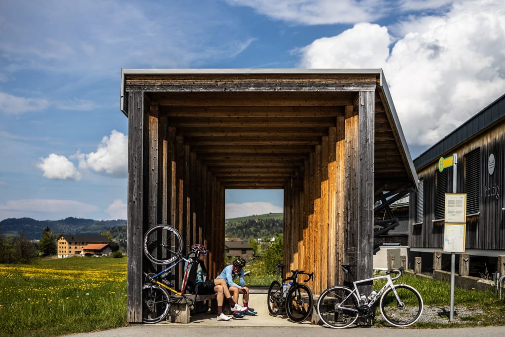 Pedal Punk Paket Zwei Radfahrer sitzen in einer Holzhütte an einer Landstraße mit ihren Fahrrädern