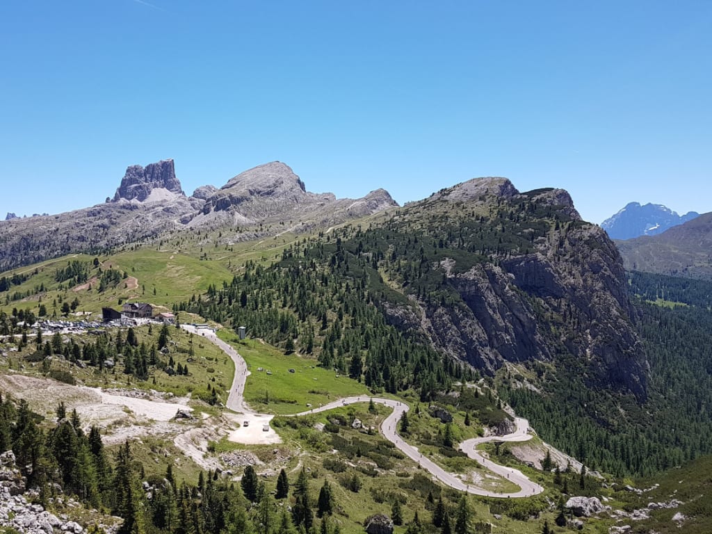 Winding mountain road in green landscape under clear blue sky