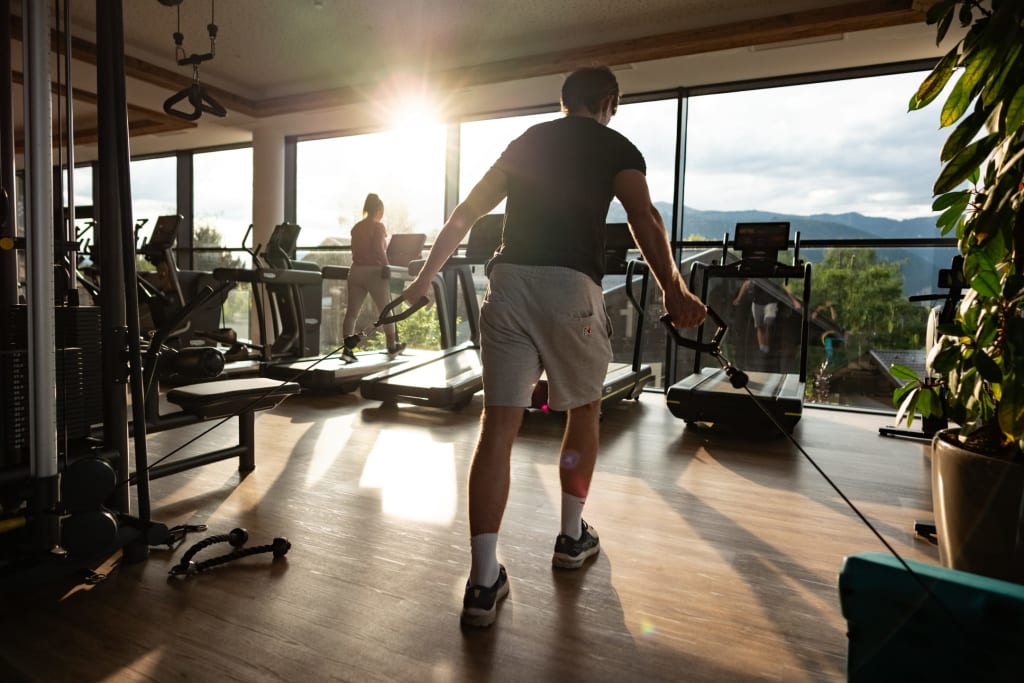 Wellness & Fitness Week for 2 People Persona che si allena con macchina a cavo in palestra con vista sul sole e montagne
