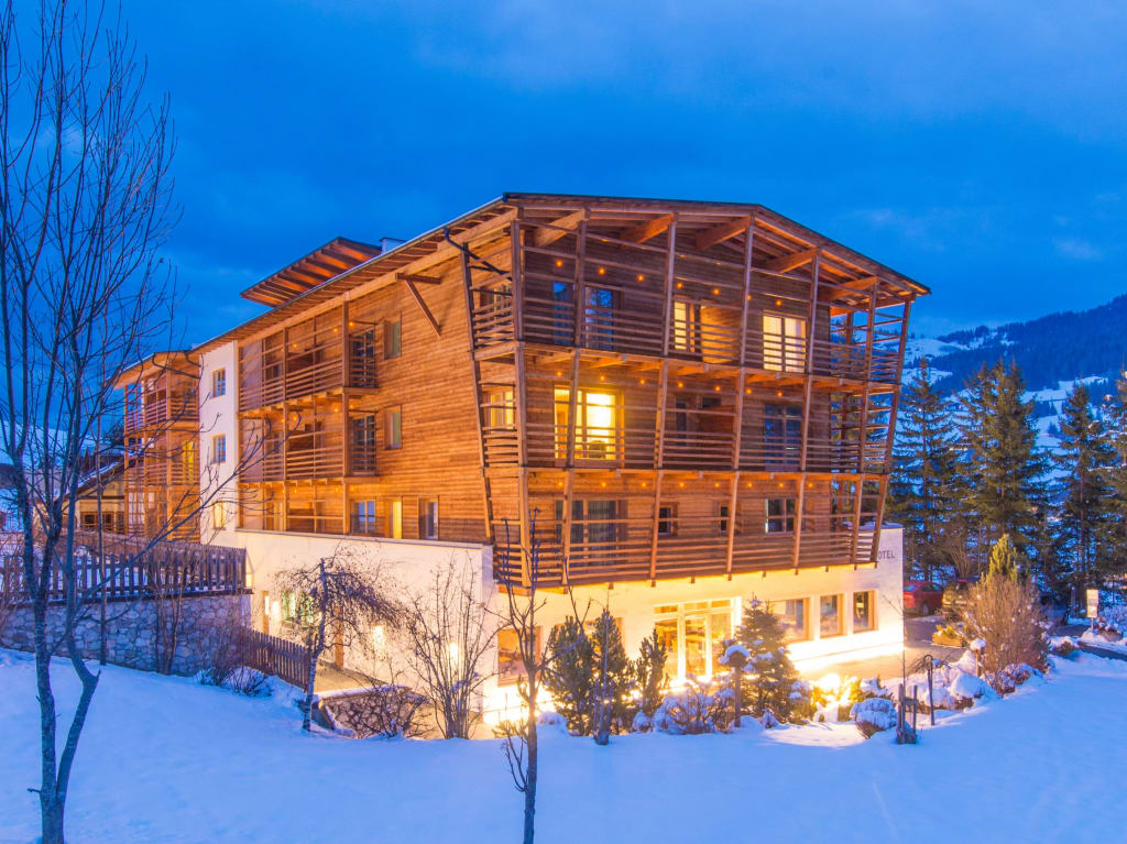 Saturday in the mountains Verlicht houten huis in sneeuw op een winteravond
