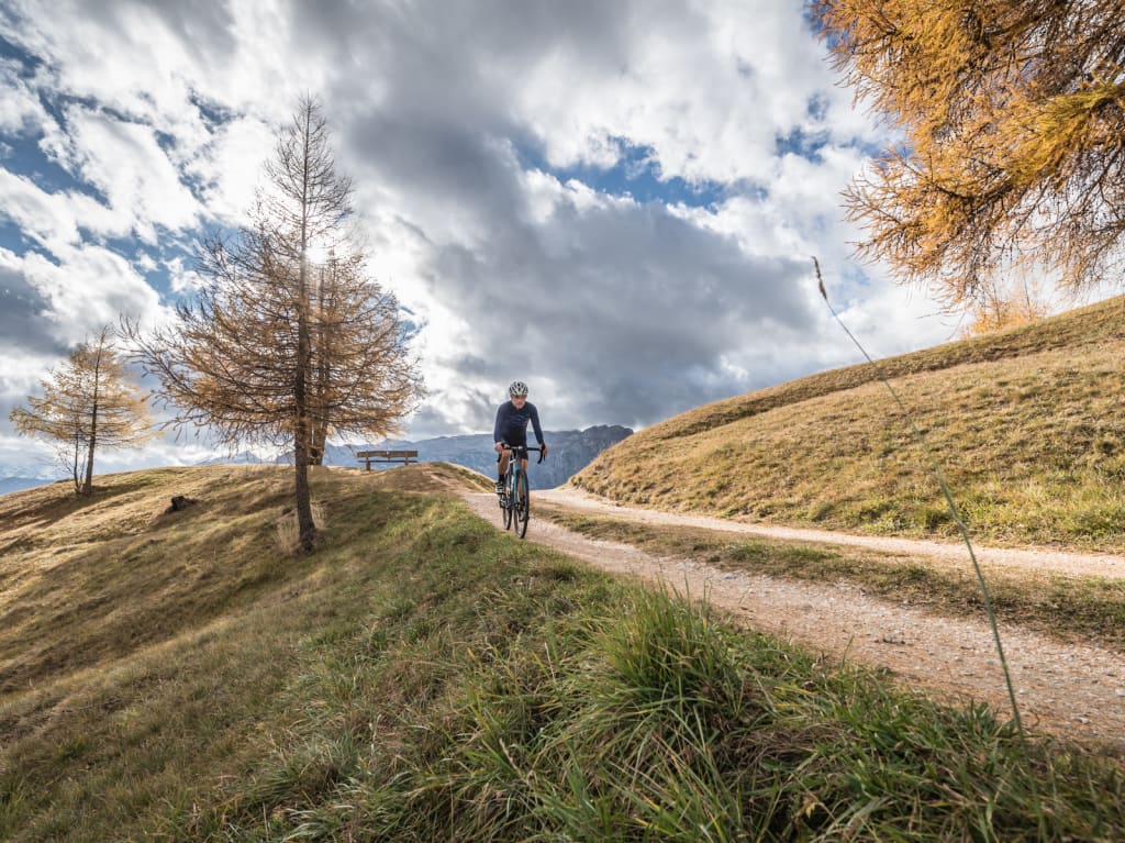 Ciclista su un sentiero stretto in paesaggio montano autunnale