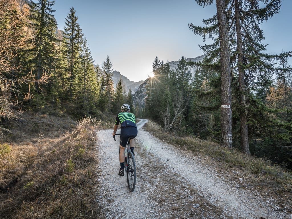 Fietser op bospad bij zonsondergang in de bergen