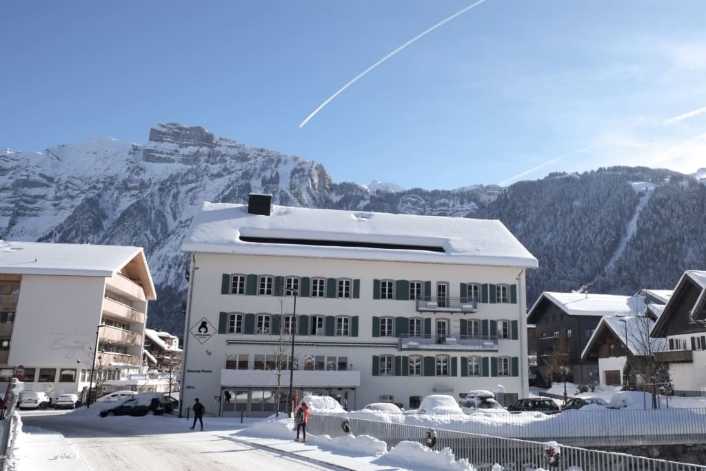 Aktion Kinderschnee Snow-covered village with mountains in the background under clear blue sky
