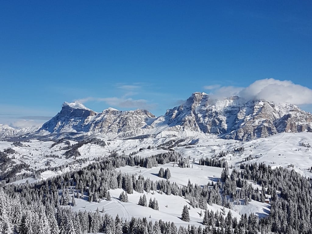 Four-Night Ski Escape Snow-covered mountains and pine trees under clear blue sky